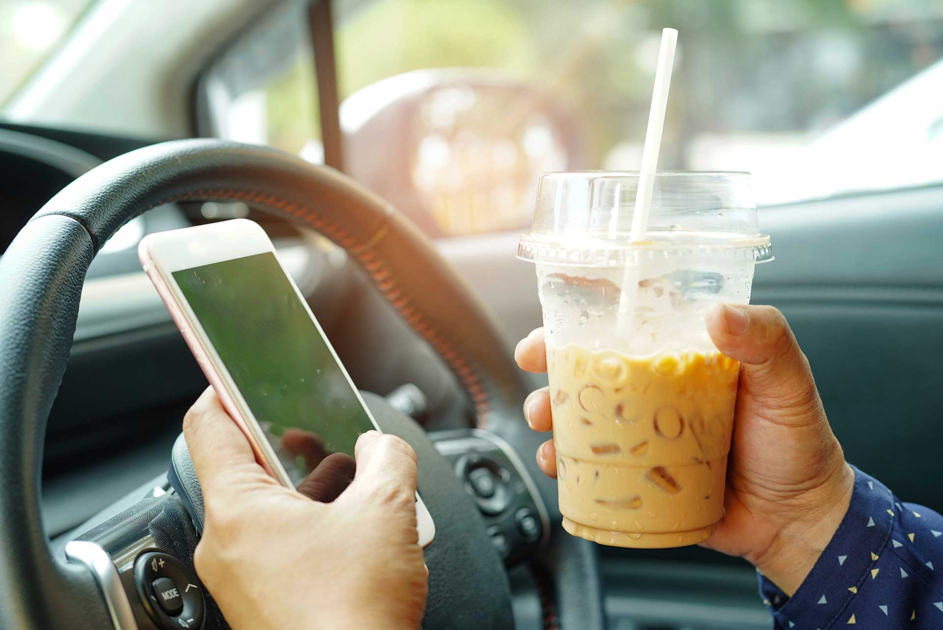 Distracted driver holding cell phone and cup of coffee | Parkville Auto Body