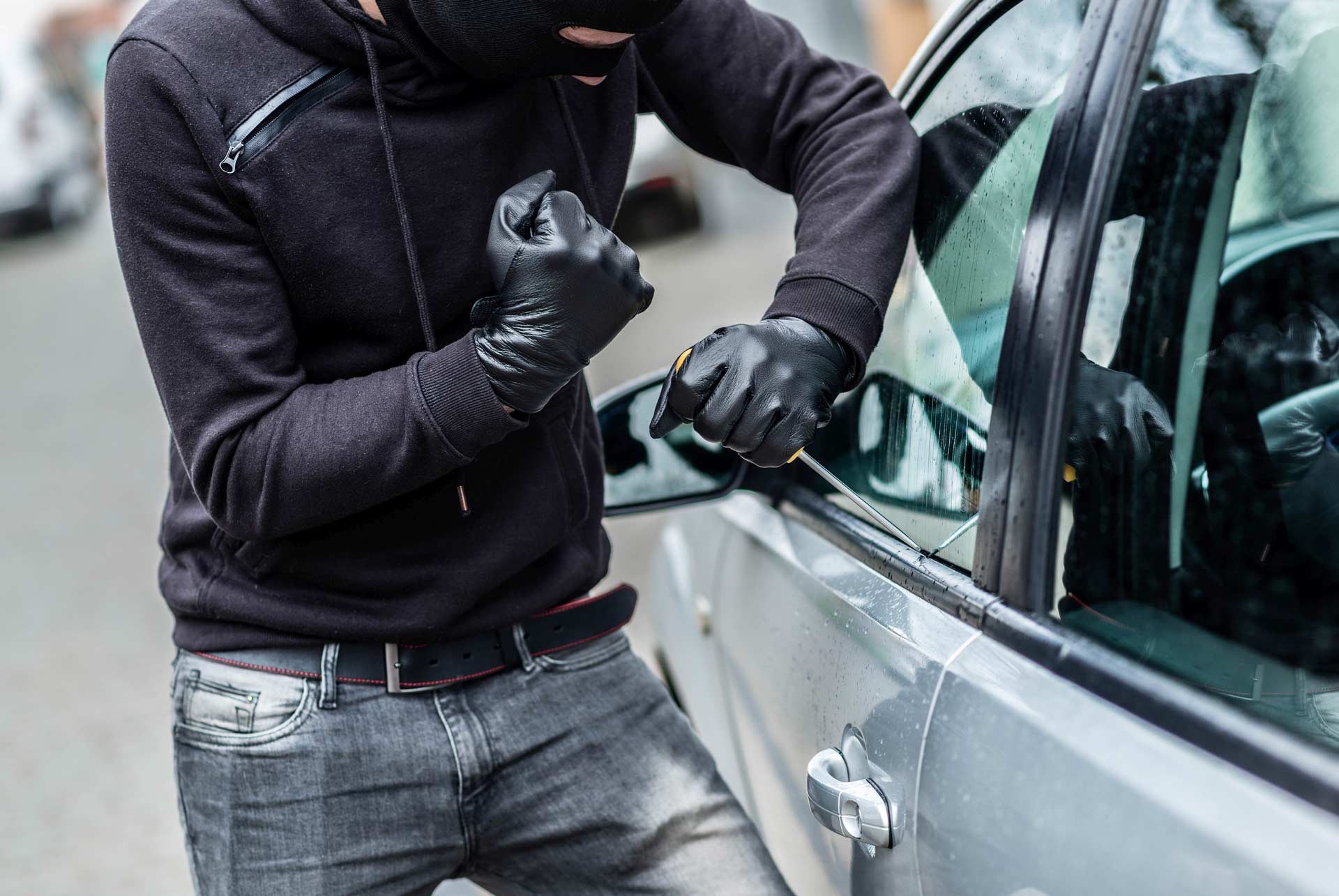 Thief breaking into a parked vehicle | Parkville Auto Body